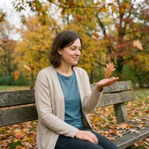 Frau sitzt auf Parkbank im Herbstwald, Augen geschlossen, hält orangefarbenes Ahornblatt